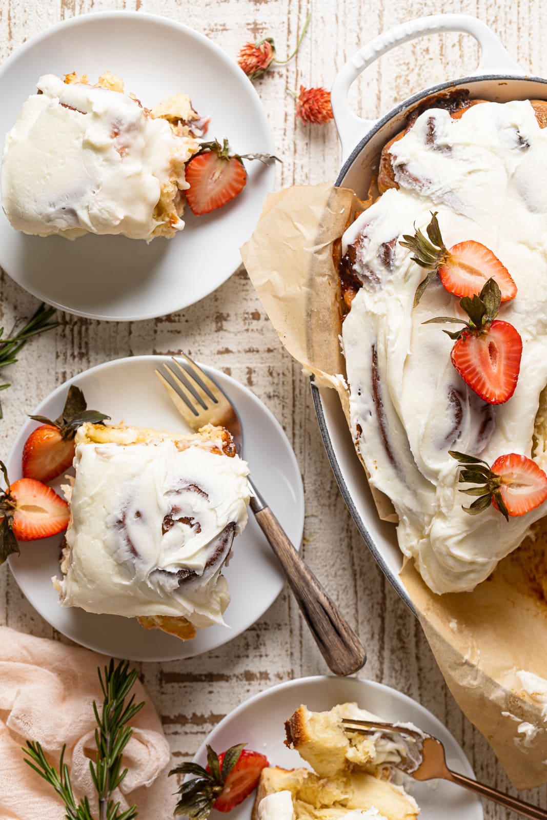 Two small plates and a Dutch oven of Strawberry Sweet Rolls with Lemon Cream Cheese Glaze