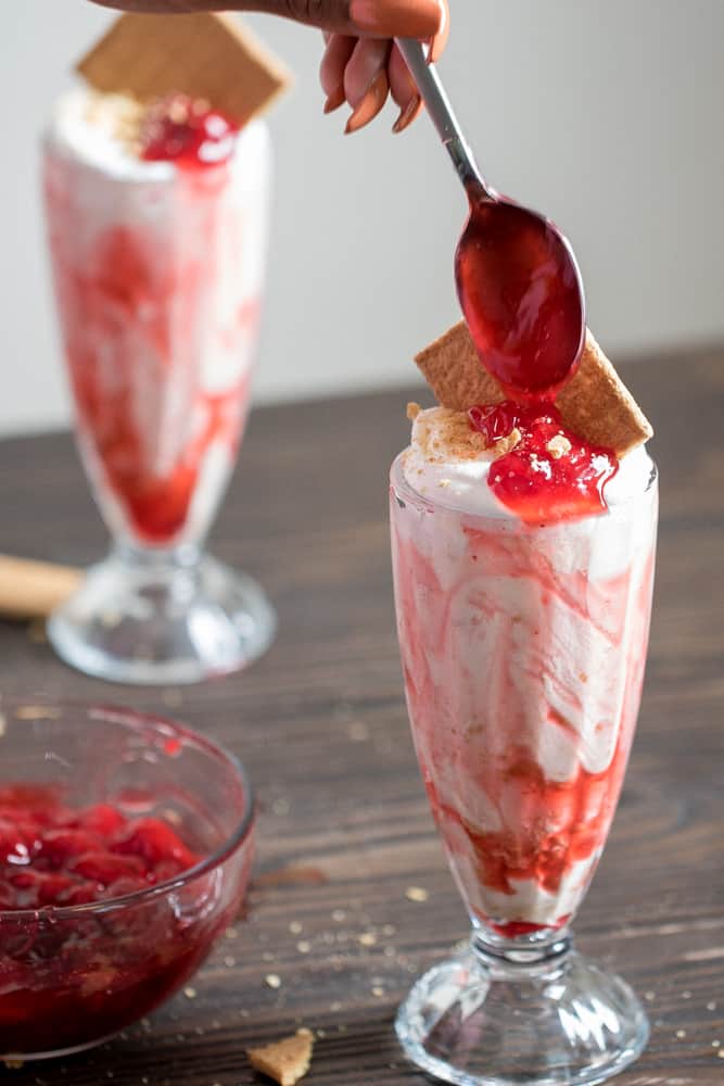 Spoon adding strawberry sauce to a Strawberry Cheesecake Milkshake.