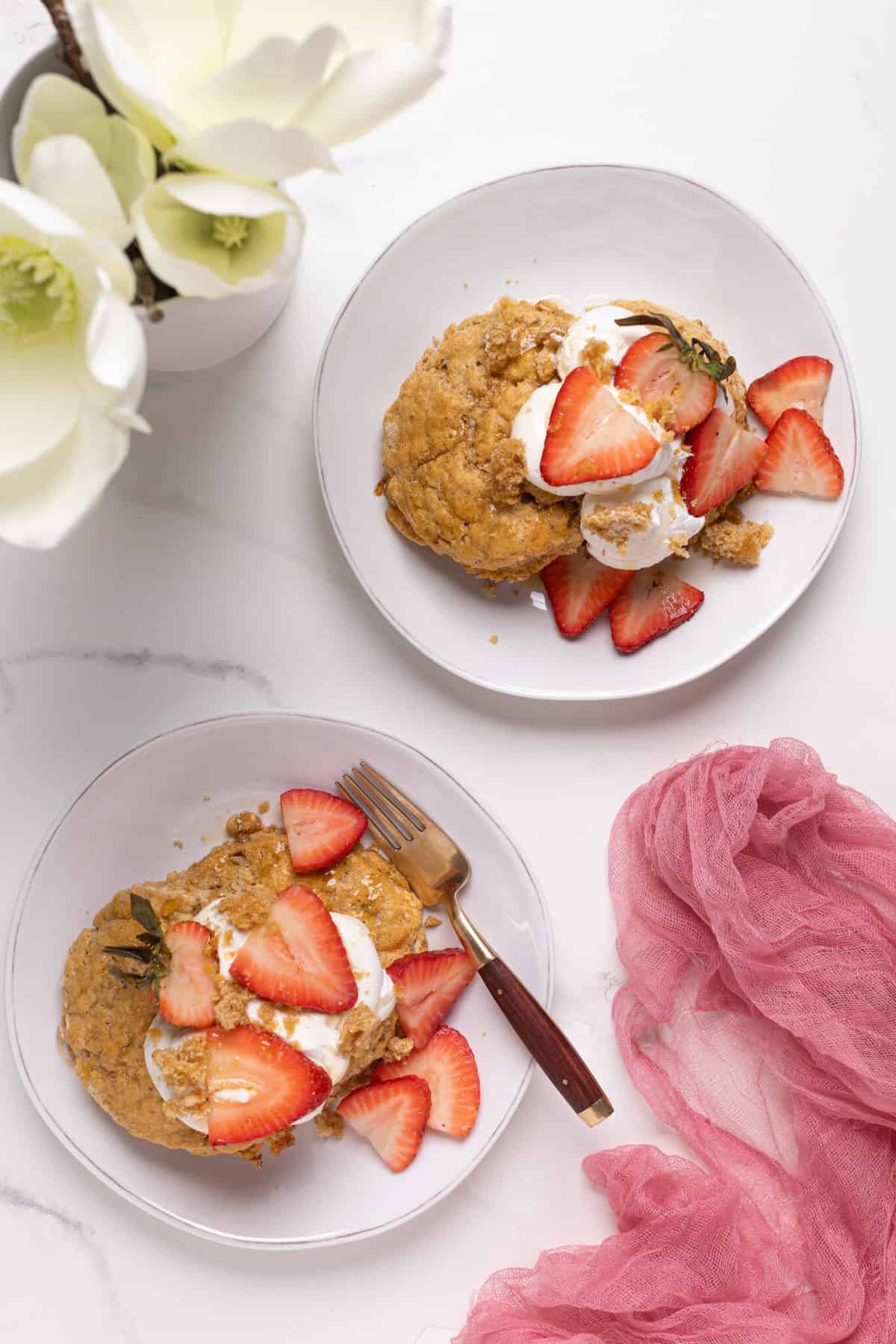 Maple Whole Wheat Oatmeal Strawberry Shortcake on a white plate with a white flour in the background and pink gauze