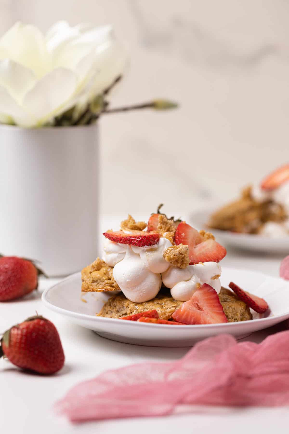 Maple Whole Wheat Oatmeal Strawberry Shortcake on a white plate with a white flour in the background and pink gauze.