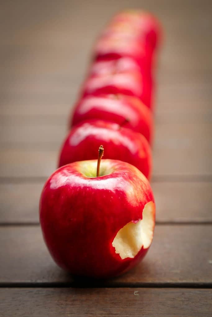 Line of apples, one of which is missing a bite.