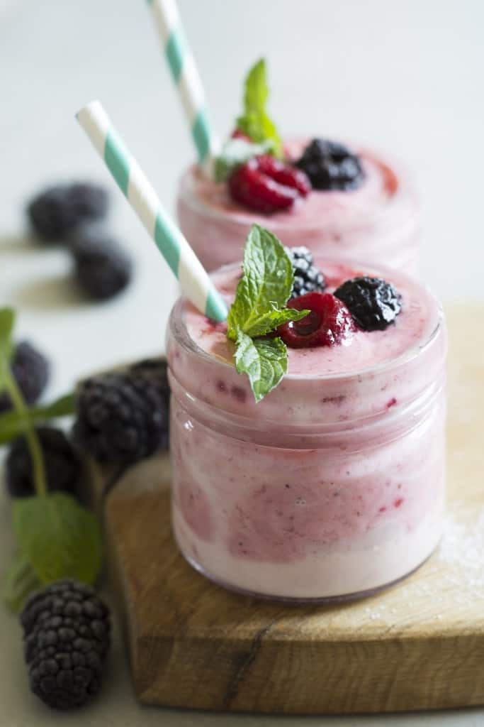 Two small jars of yogurt topped with fruit.