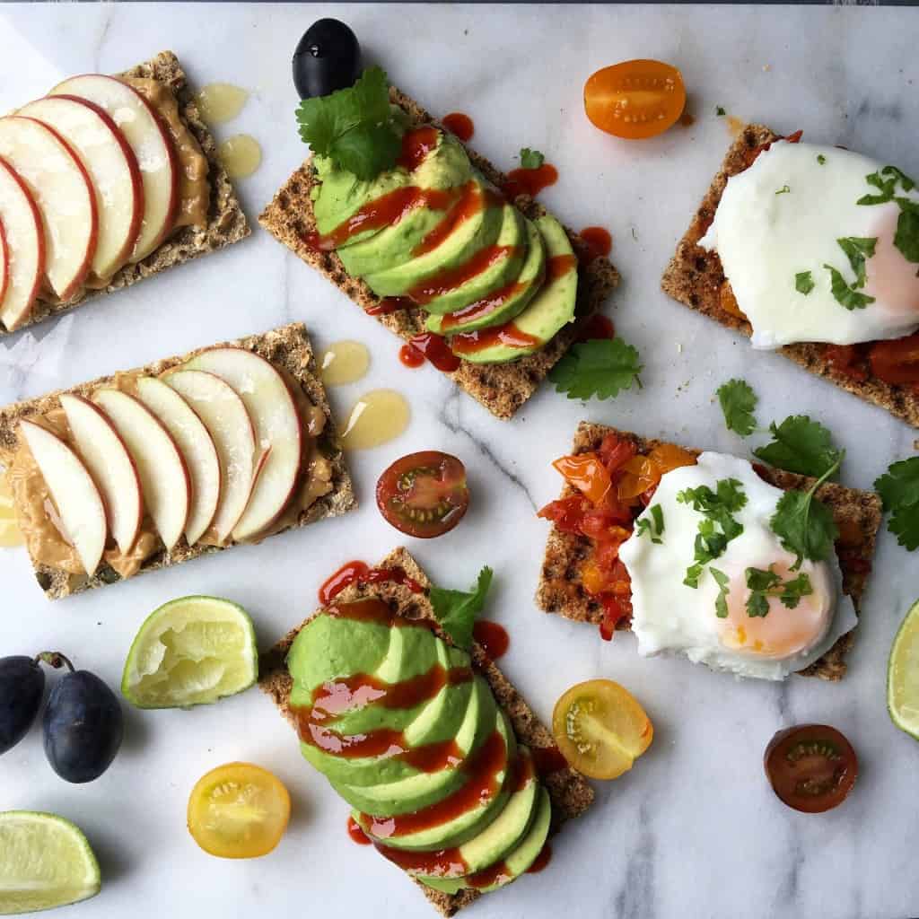 Slices of avocados, apples, and other foods on a marble countertop.