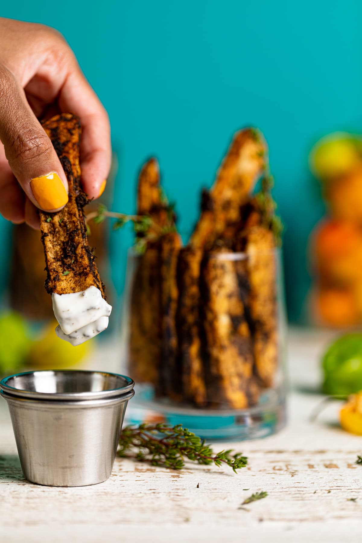 Hand dipping a Crispy Baked Jerk Potato Wedge into dairy-free garlic lime sauce