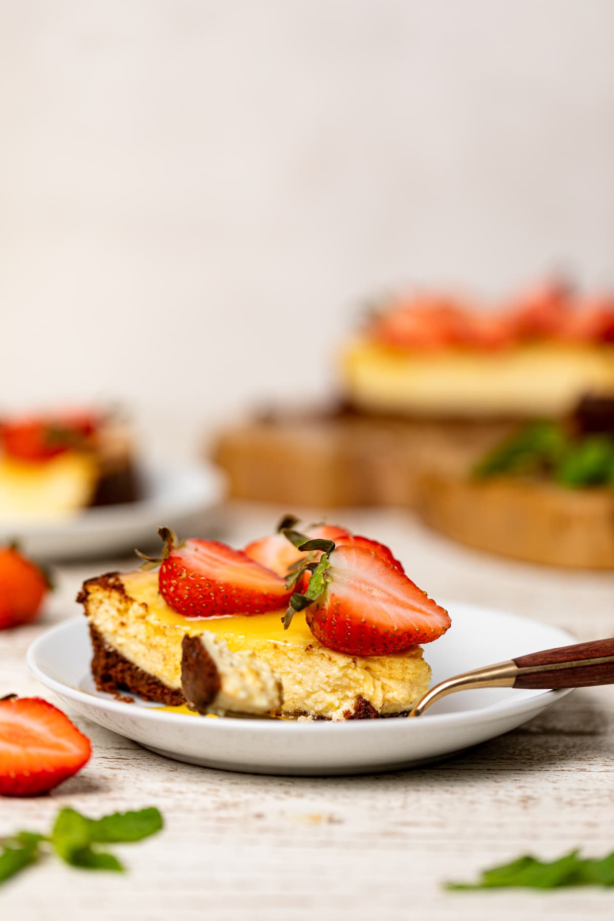 Slice of Mango Cheesecake with Chocolate Graham Cracker Crust on a plate with a fork.