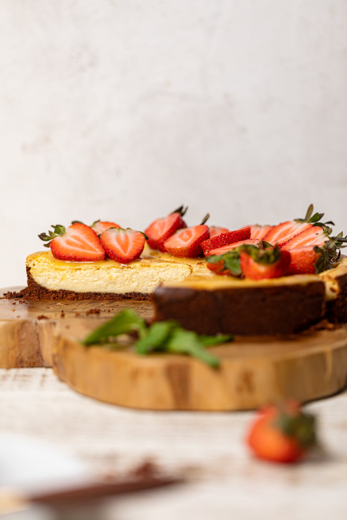 Mango Cheesecake with Chocolate Graham Cracker Crust on a thick wooden board.