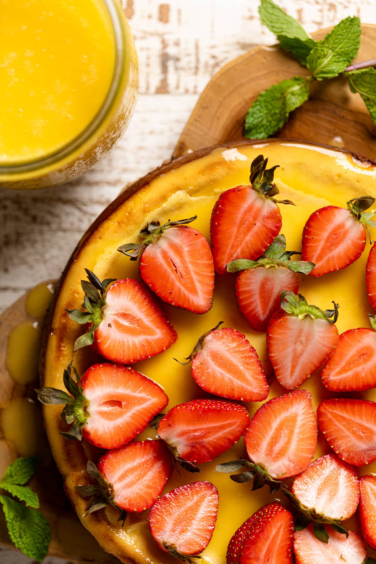 Mango Cheesecake with Chocolate Graham Cracker Crust topped with halved strawberries.