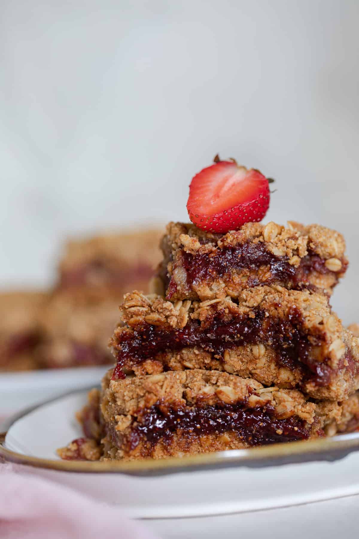 Strawberry half on top of a stack of Vegan Strawberry Peanut Butter Oatmeal Bars.