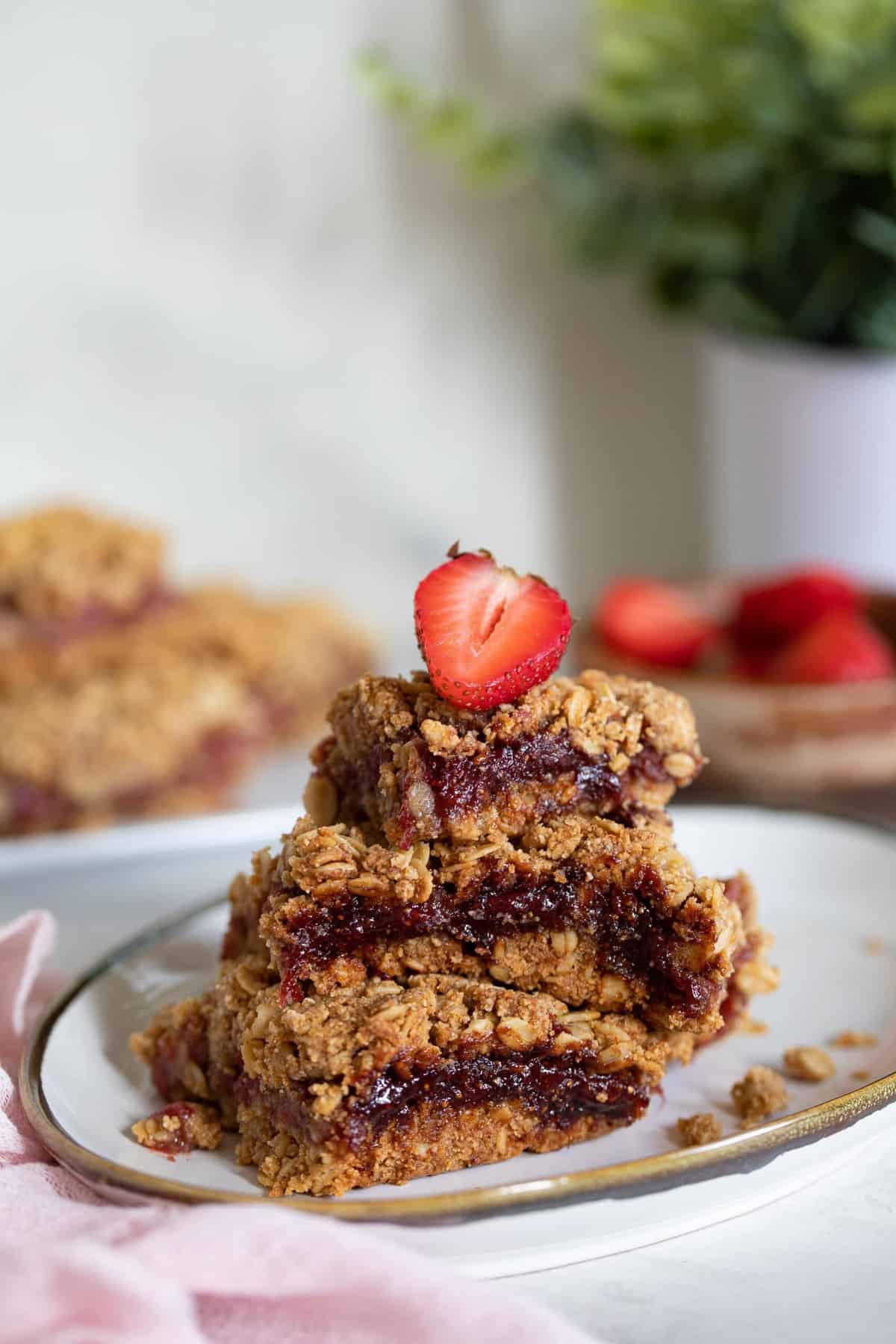 Stack of Vegan Strawberry Peanut Butter Oatmeal Bars topped with a strawberry.