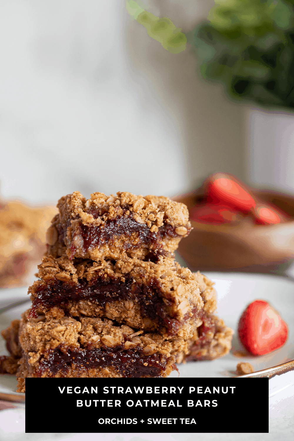 Stack of Vegan Strawberry Peanut Butter Oatmeal Bars on a plate with a strawberry.