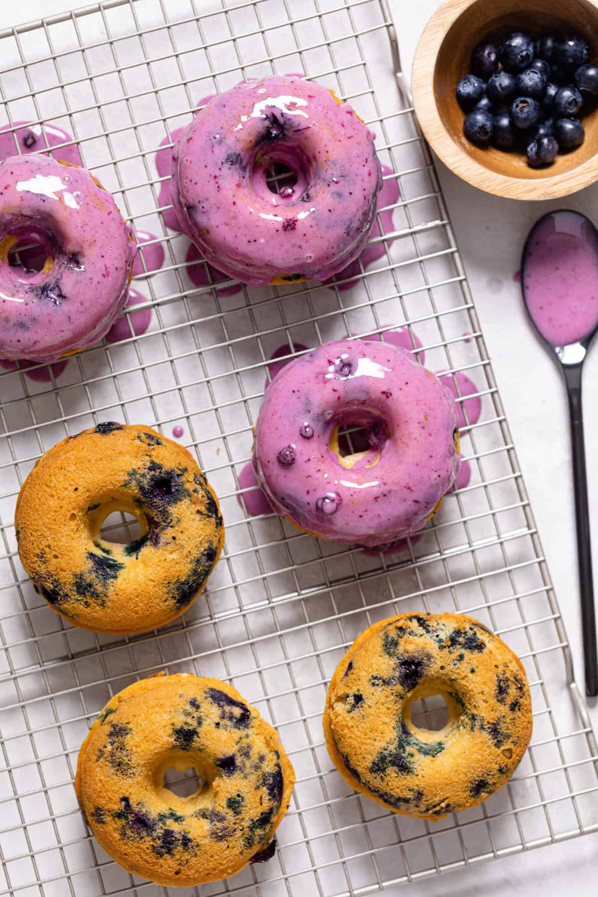 Blueberry glaze being added to Blueberry Vegan Donuts.