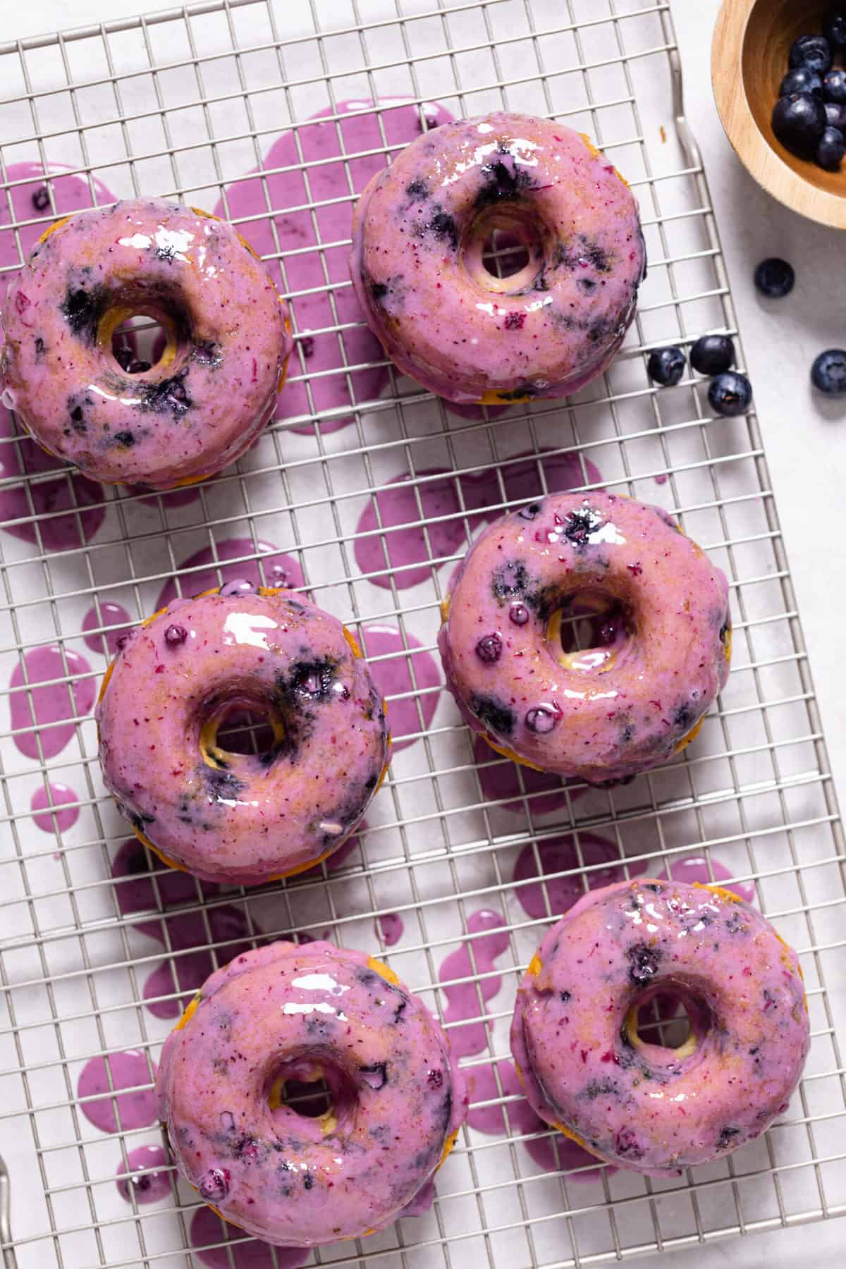 Blueberry Vegan Donuts with Blueberry Glaze on a wire rack with blueberries.