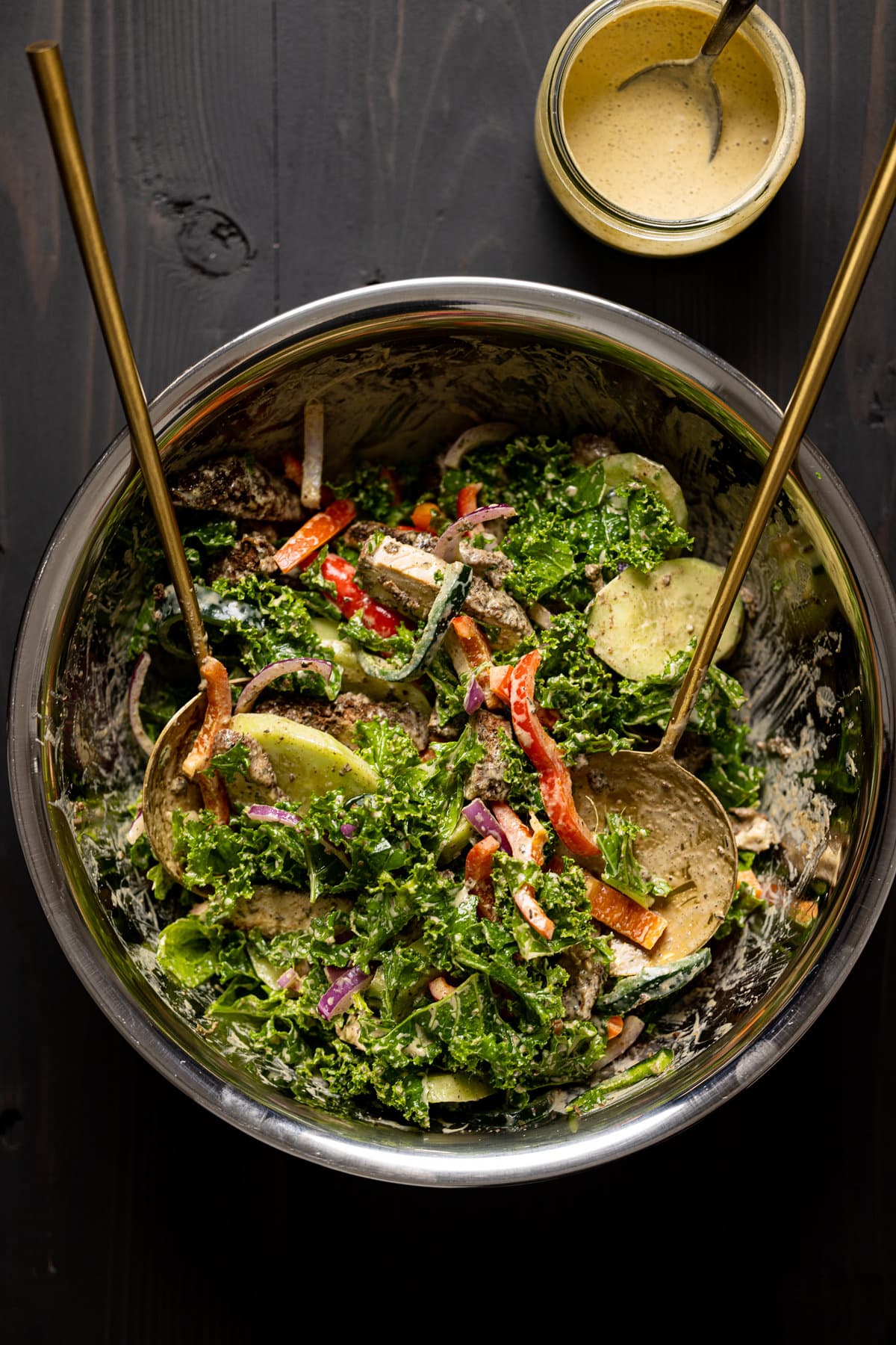 Two spoons tossing a bowl of Baked Jamaican Jerk Chicken Salad