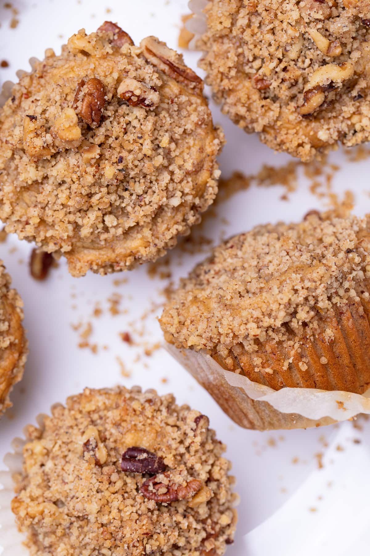 Vegan Banana Muffins with cinnamon streusel on a white plate, one of which is lying down.