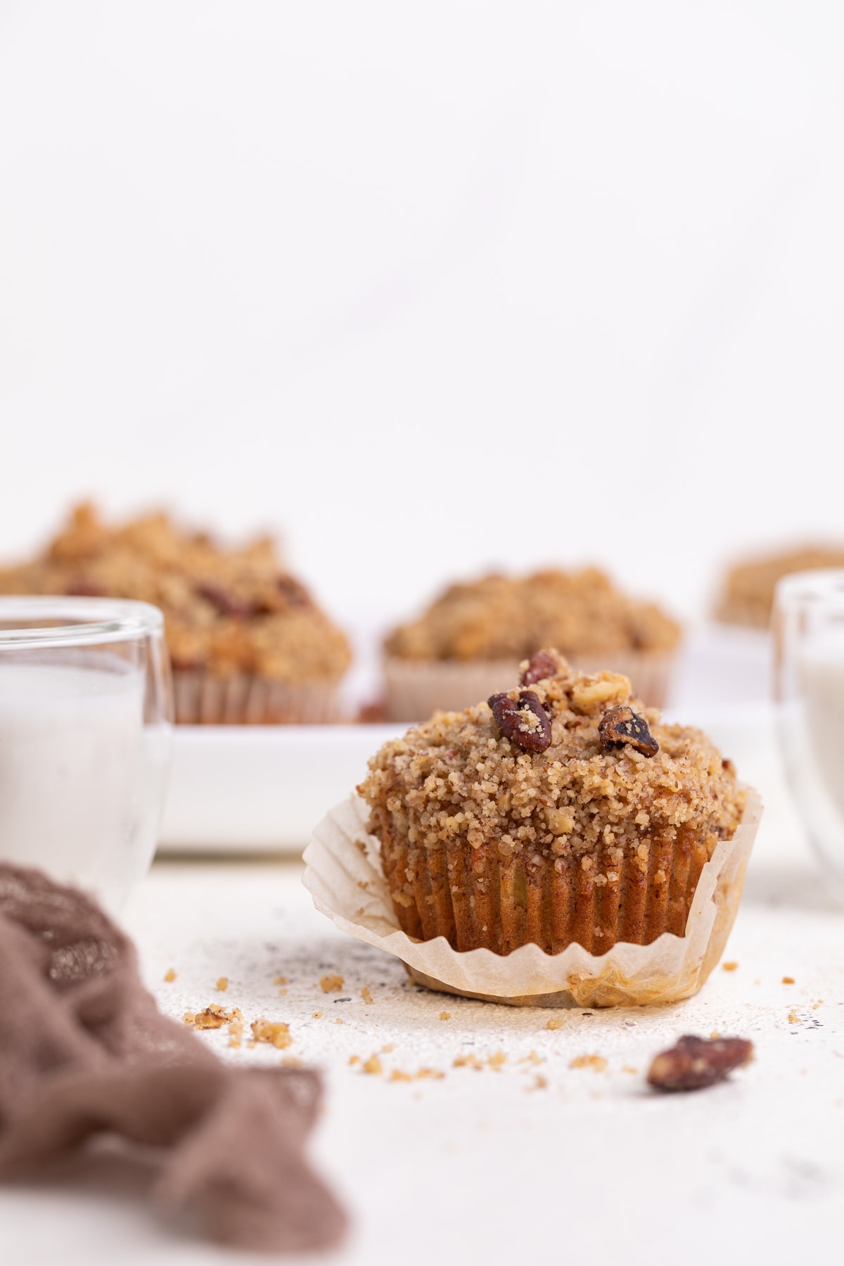 Vegan Banana Muffin with cinnamon streusel next to a plate of muffins.