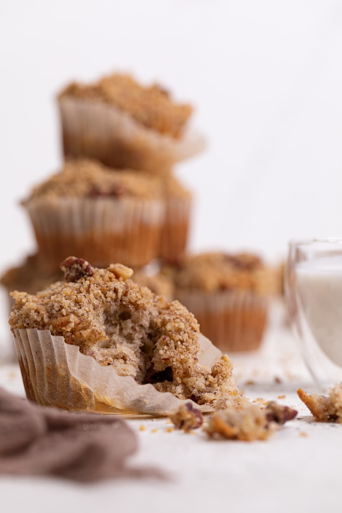 Vegan Cinnamon Banana Crumble Muffins piled on a white table.