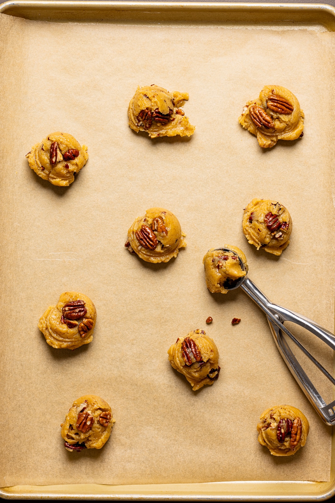 Scooped cookie dough on a baking sheet with parchment paper.