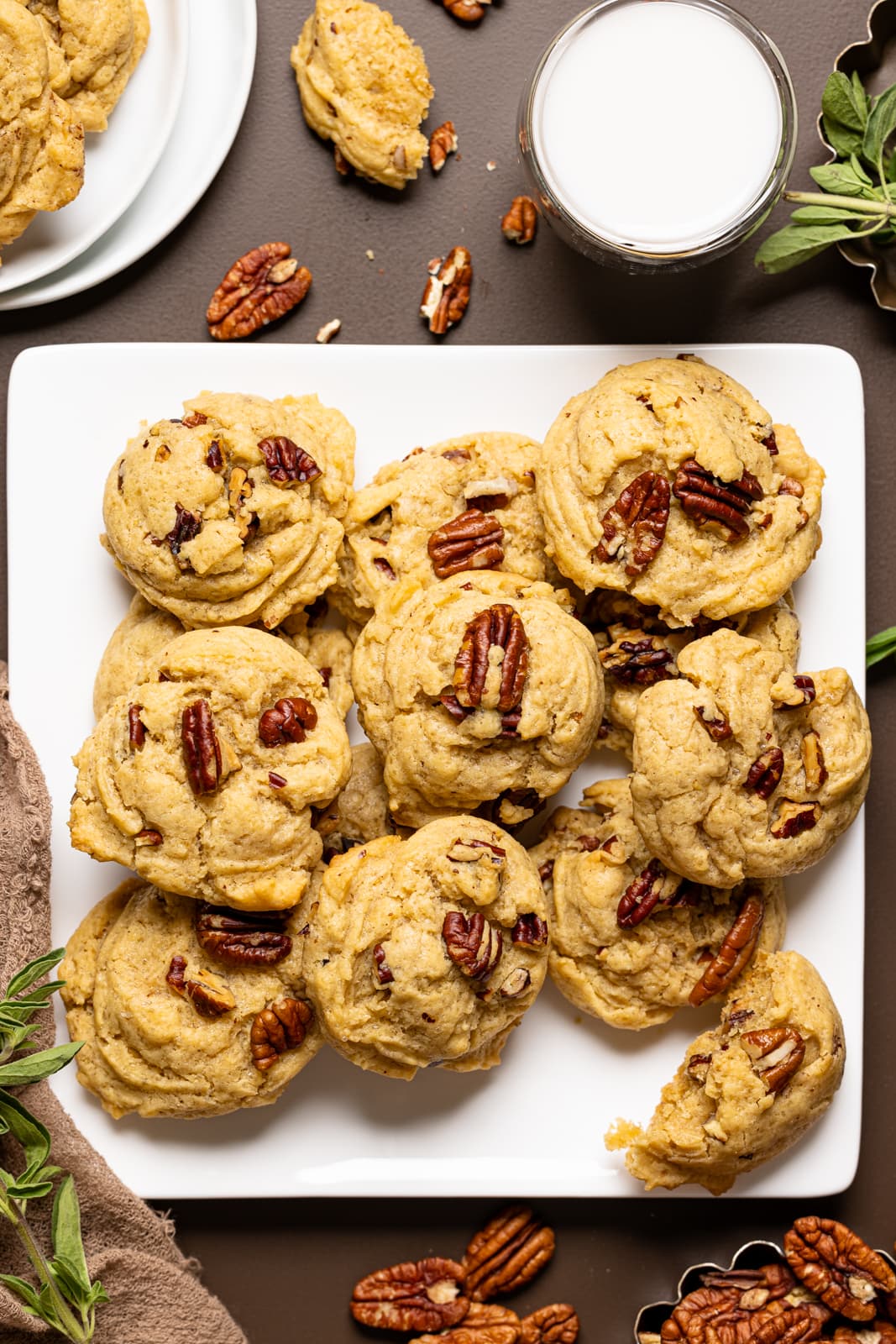 Baked cookies on a white plate with chopped pecans and herbs.