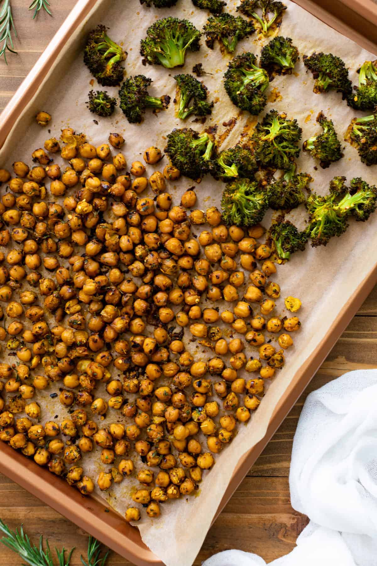 Chickpeas and broccoli on a lined baking sheet.