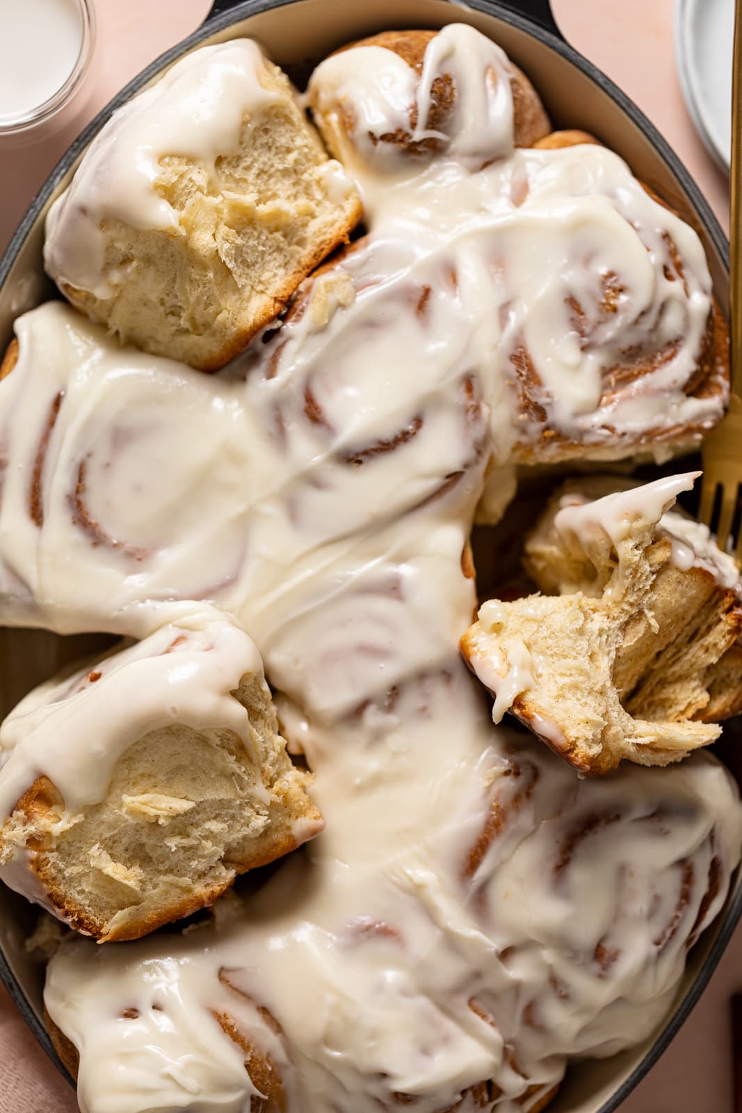 Fork grabbing Cinnamon Rolls from a baking dish.