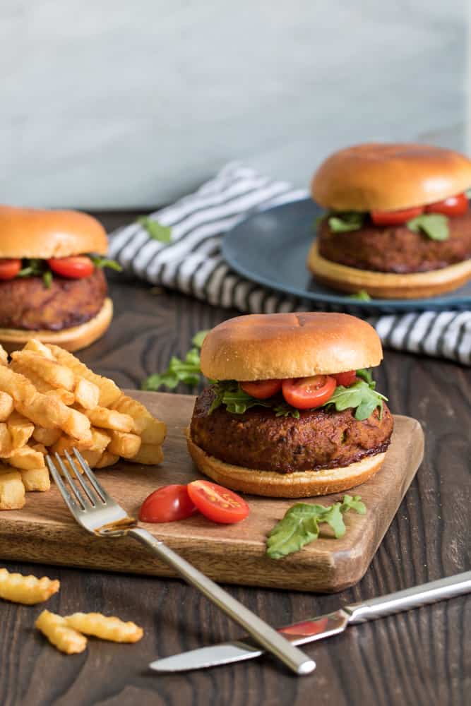 Spicy Barbeque Lentil Quinoa Vegan Burgers with fries on a wooden board.