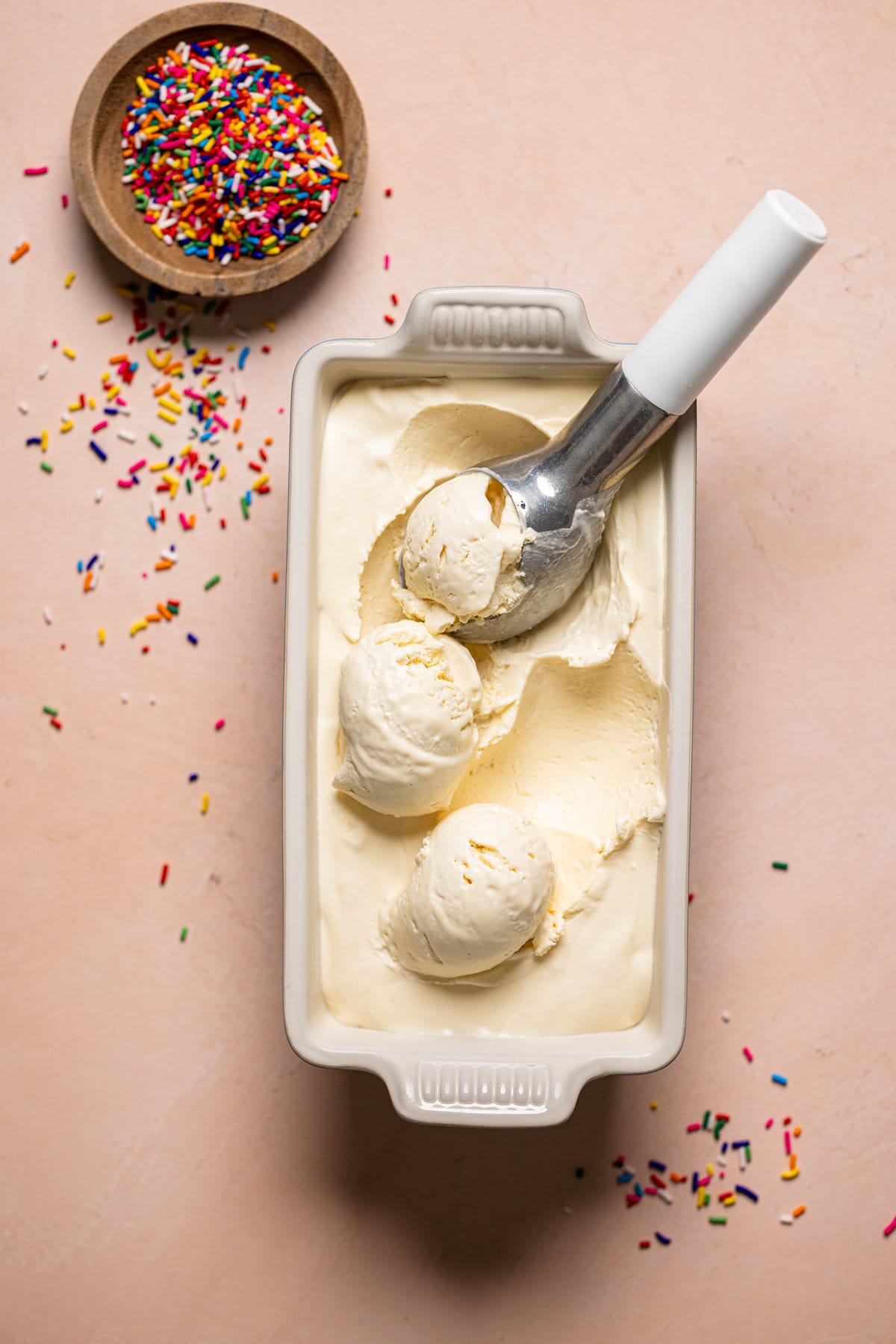 Ice cream scoop in a container of No-Churn Vanilla Ice Cream.