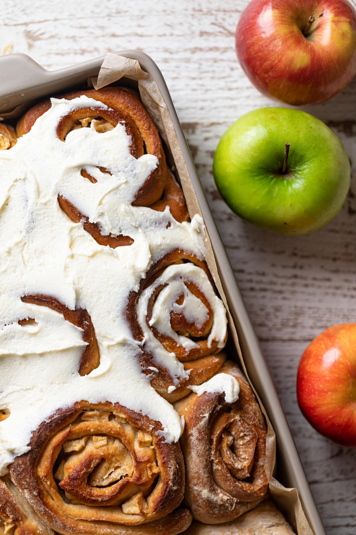 Baking dish of Overnight Vegan Apple Cinnamon Rolls next to apples