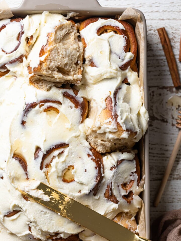 Butter knife of a baking dish of Overnight Vegan Apple Cinnamon Rolls