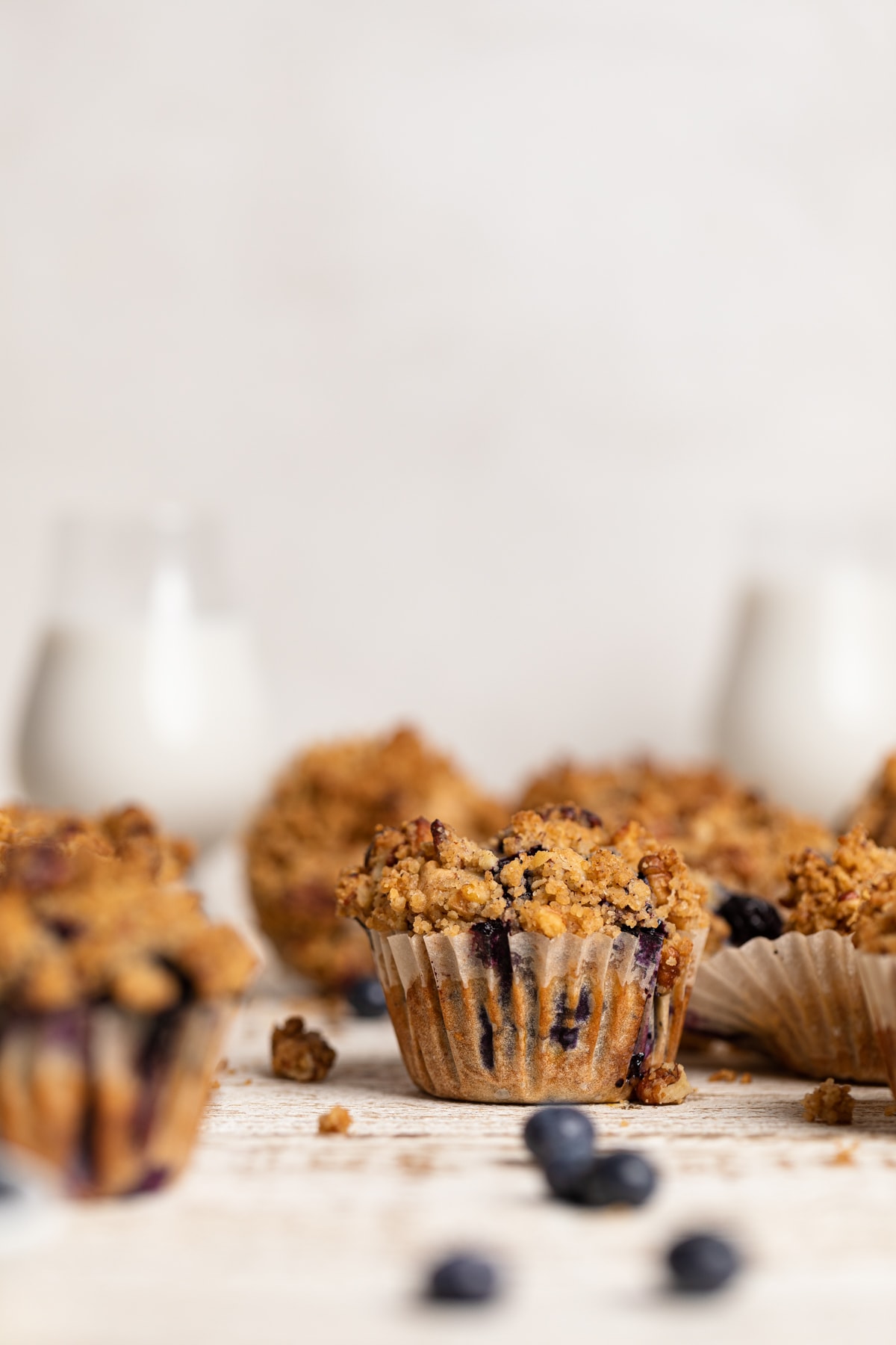 Vegan Banana Blueberry Pecan Crumble Muffins on a white, wooden table