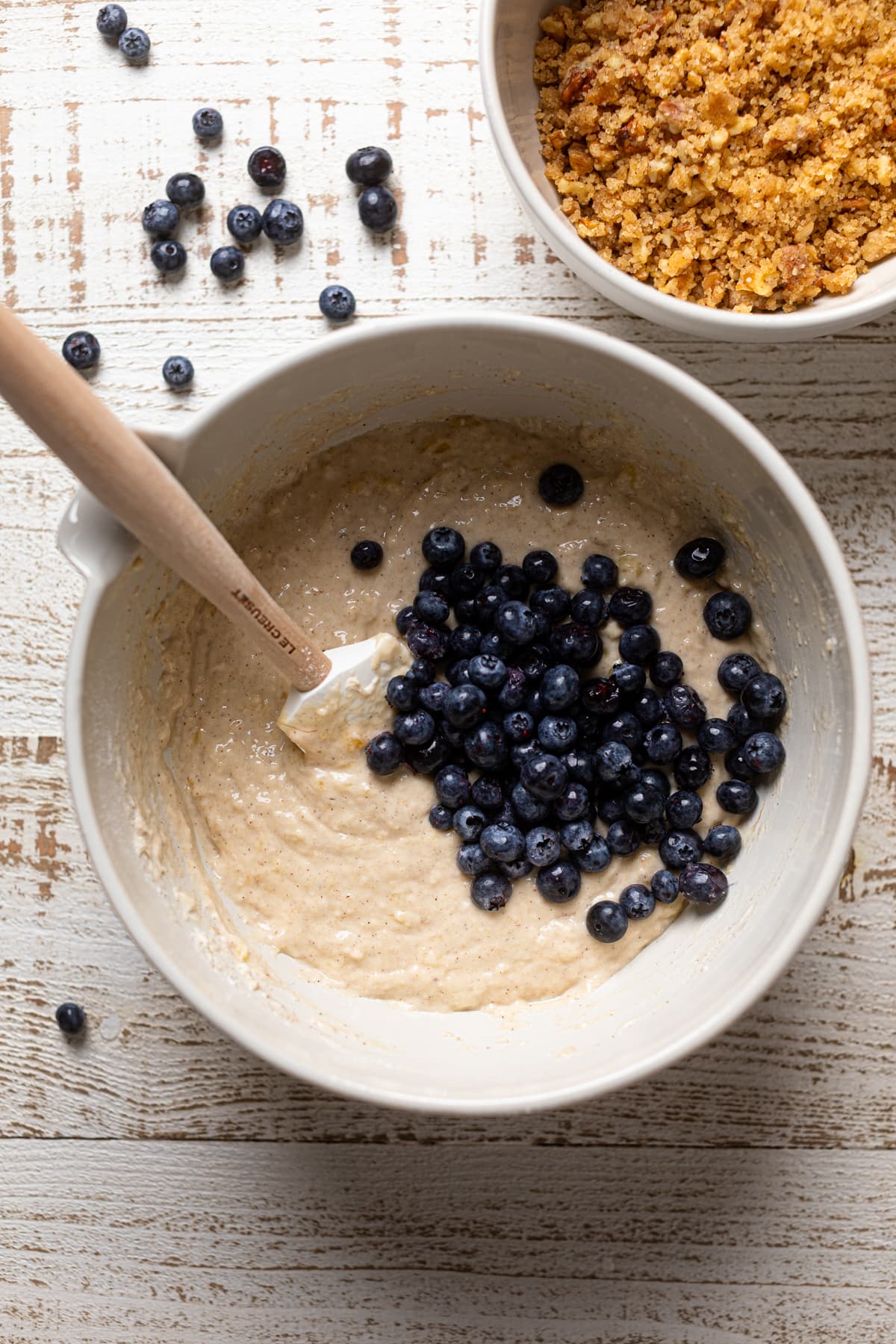 Vegan Banana Blueberry Pecan Crumble Muffin batter topped with a pile of blueberries