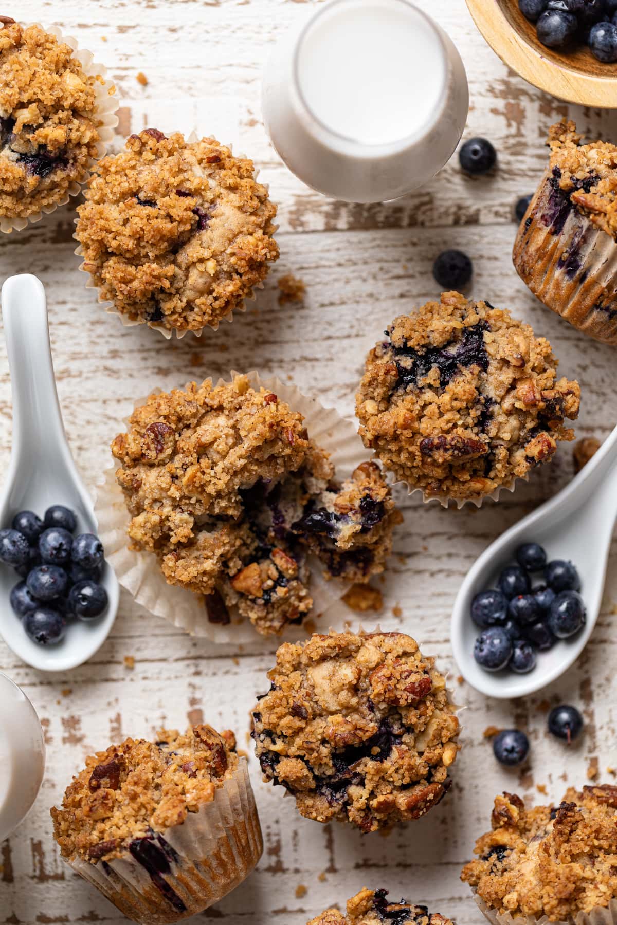 Vegan Banana Blueberry Pecan Crumble Muffins with spoons of blueberries