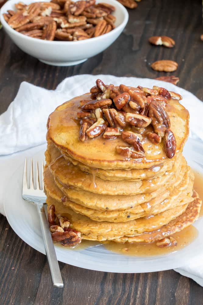 Pumpkin Quinoa Pancakes with Praline Syrup stacked on a plate.