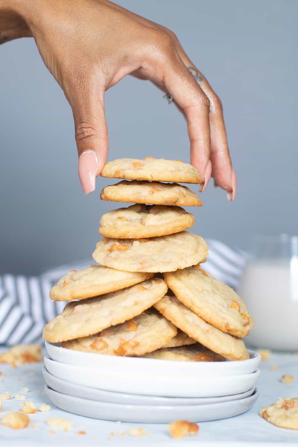 Woman grabbing a Soft and Crisp Crinkled Butterscotch Cookie from a stack.