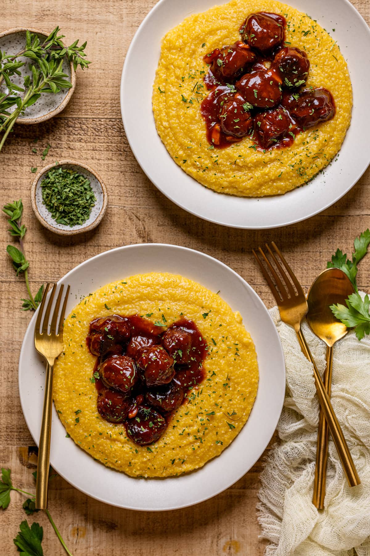 Two plates of Vegan BBQ Chickpea Meatballs with Polenta