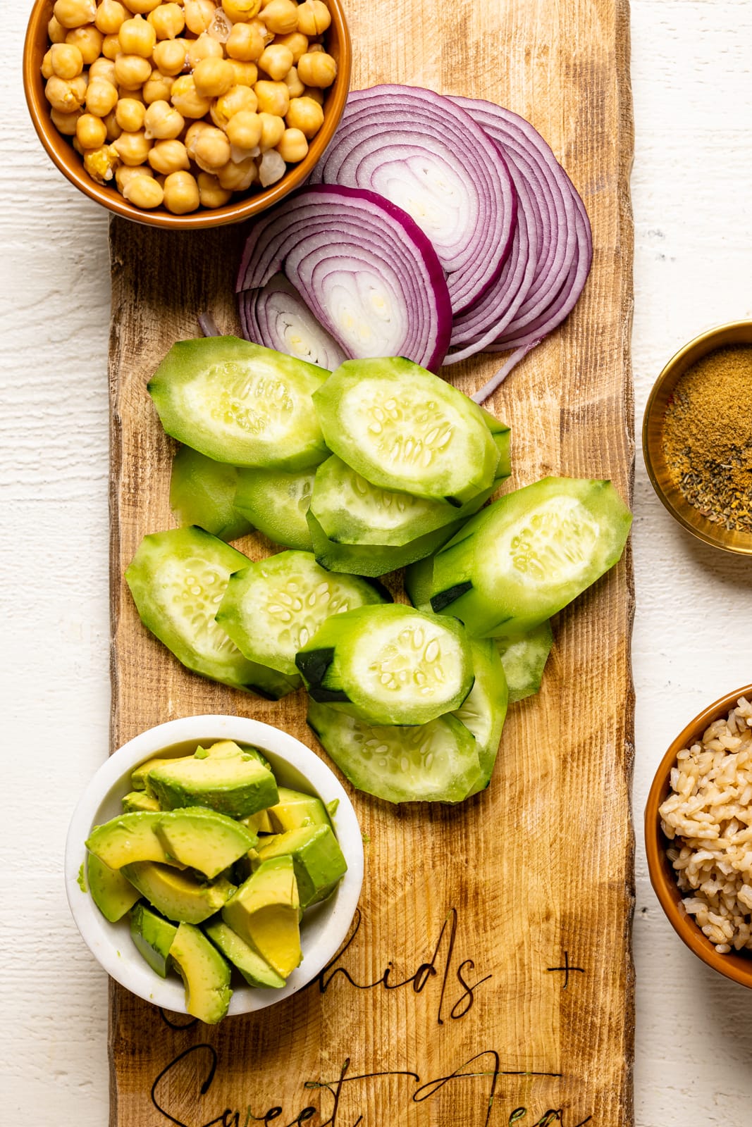 Chopped veggies on a cutting board with chickpeas and brown rice.