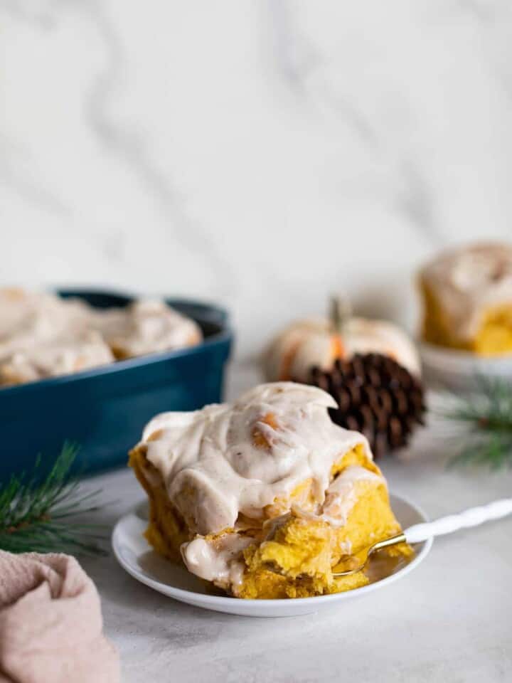 Pumpkin Chai Cinnamon Roll on a small plate with a fork