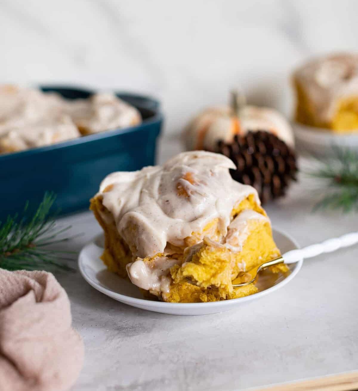 Pumpkin Chai Cinnamon Roll on a small plate with a fork