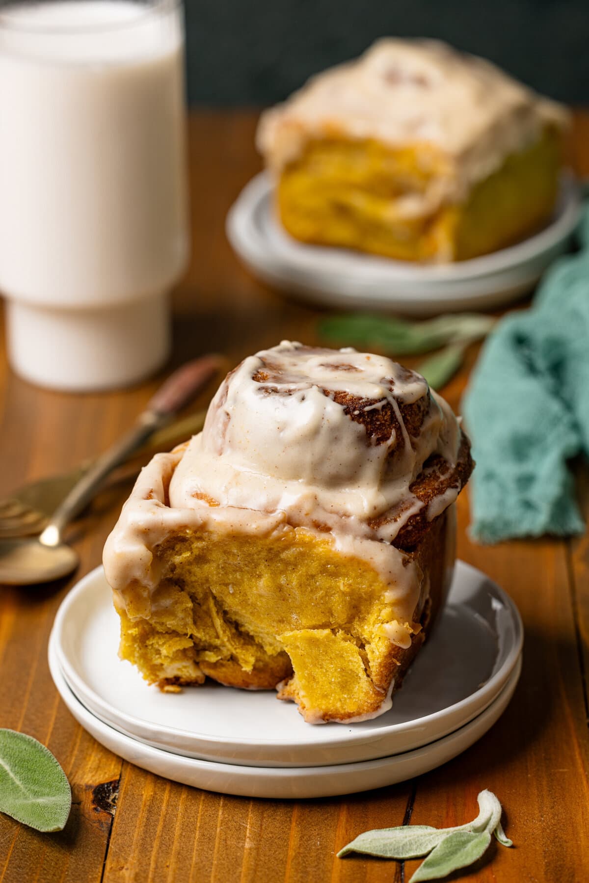 Cinnamon rolls on white plates with a glass of milk.