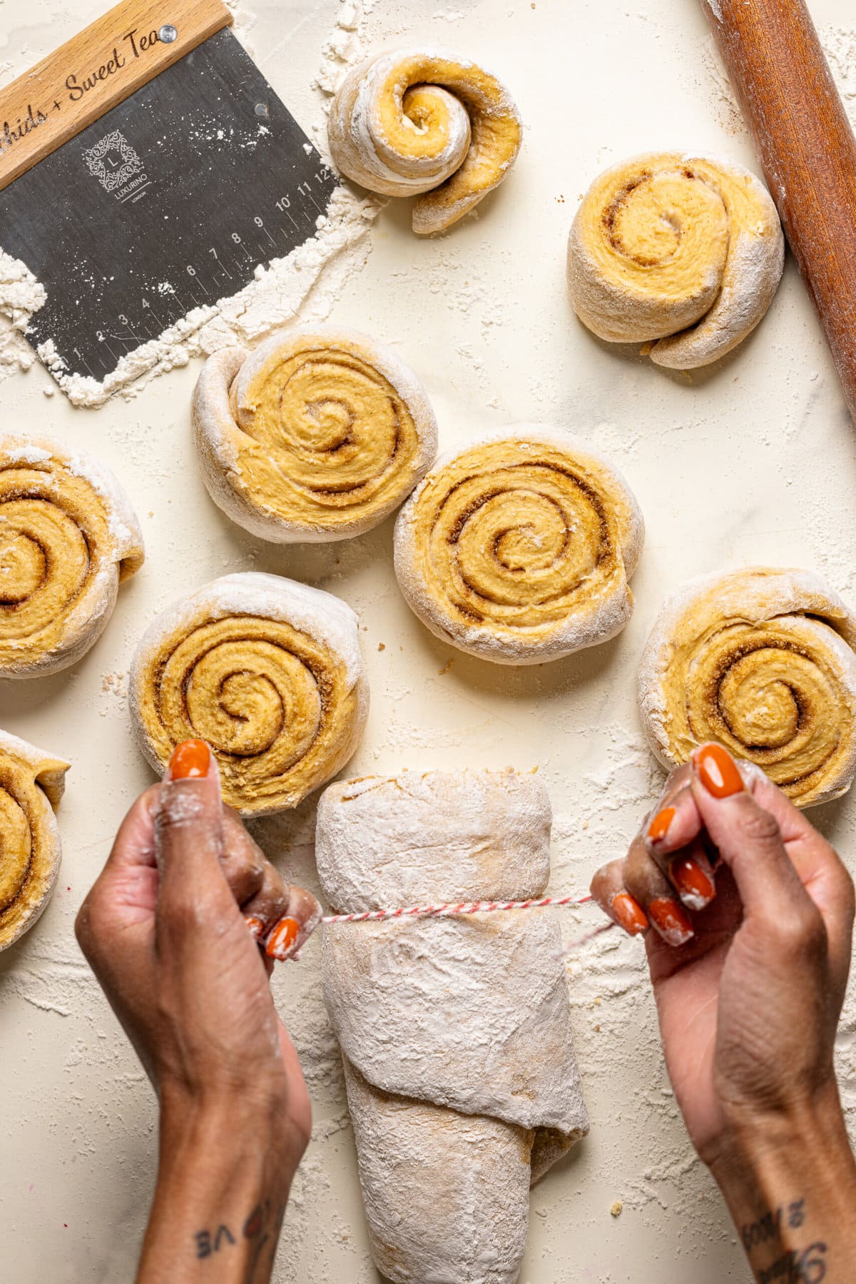 Cinnamon roll dough being cut into swirls. 