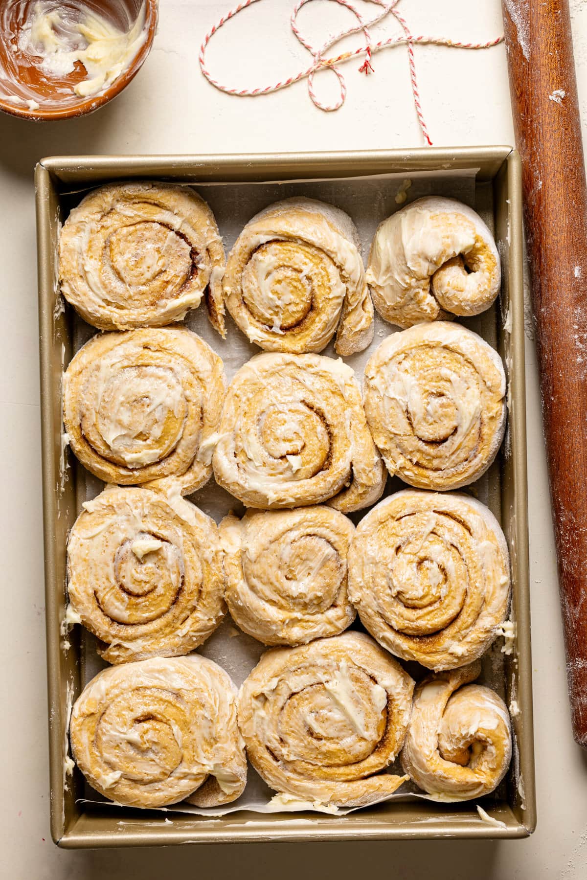 Cinnamon rolls in a baking dish and a rolling pin.