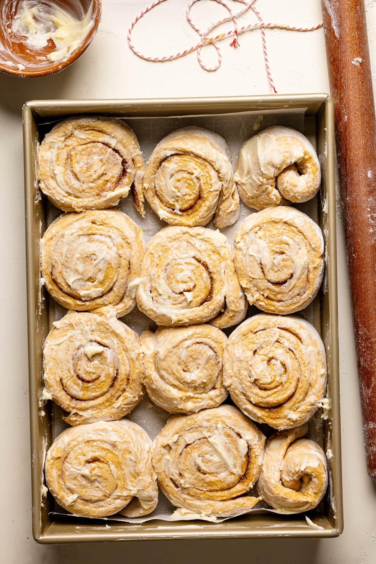 Cinnamon rolls in a baking dish and a rolling pin.