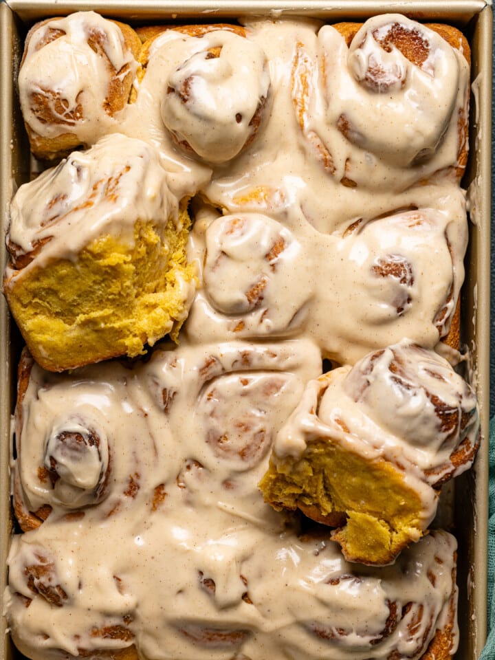 Frosted and uplifted rolls in a baking dish.