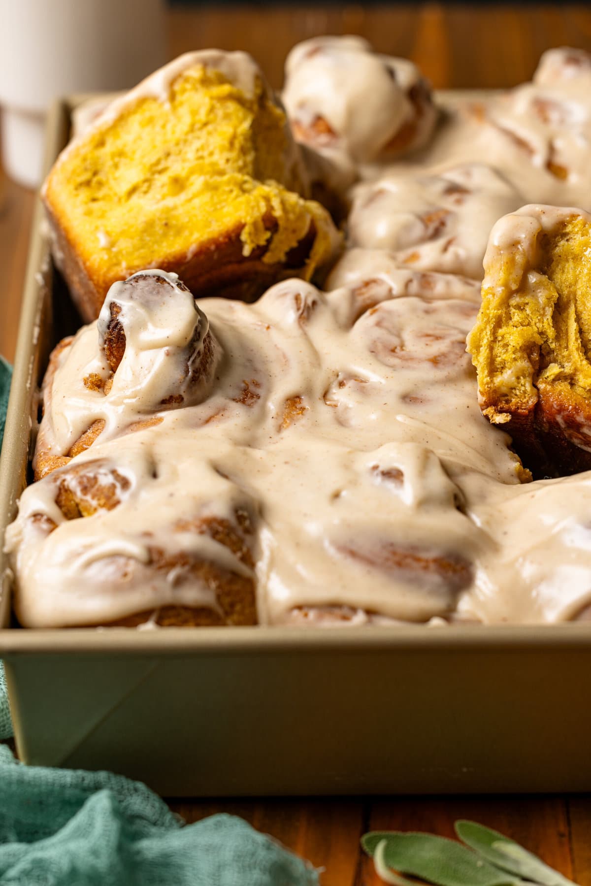 Lifted cinnamon rolls in a baking dish.