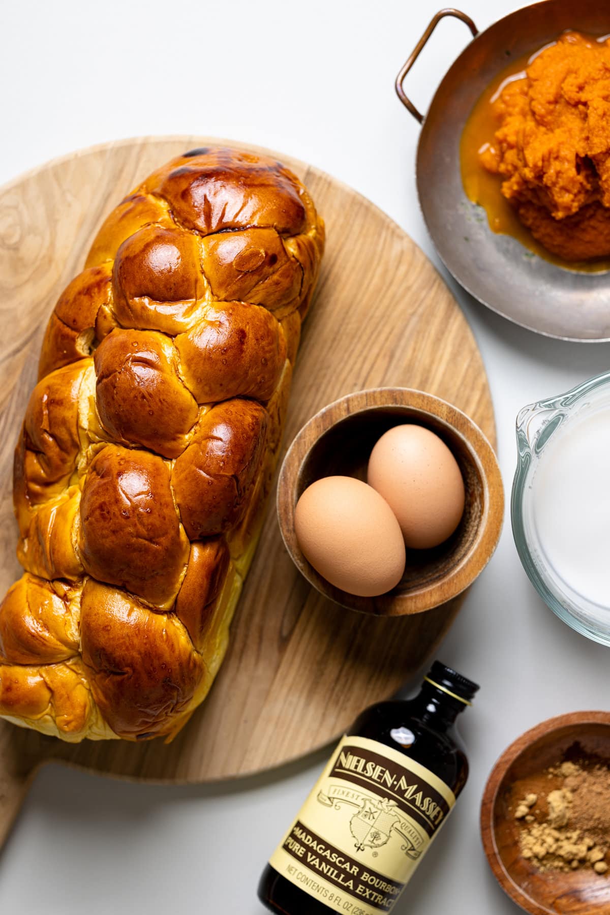 Loaf of brioche bread and eggs on a cutting board surrounded by other ingredients