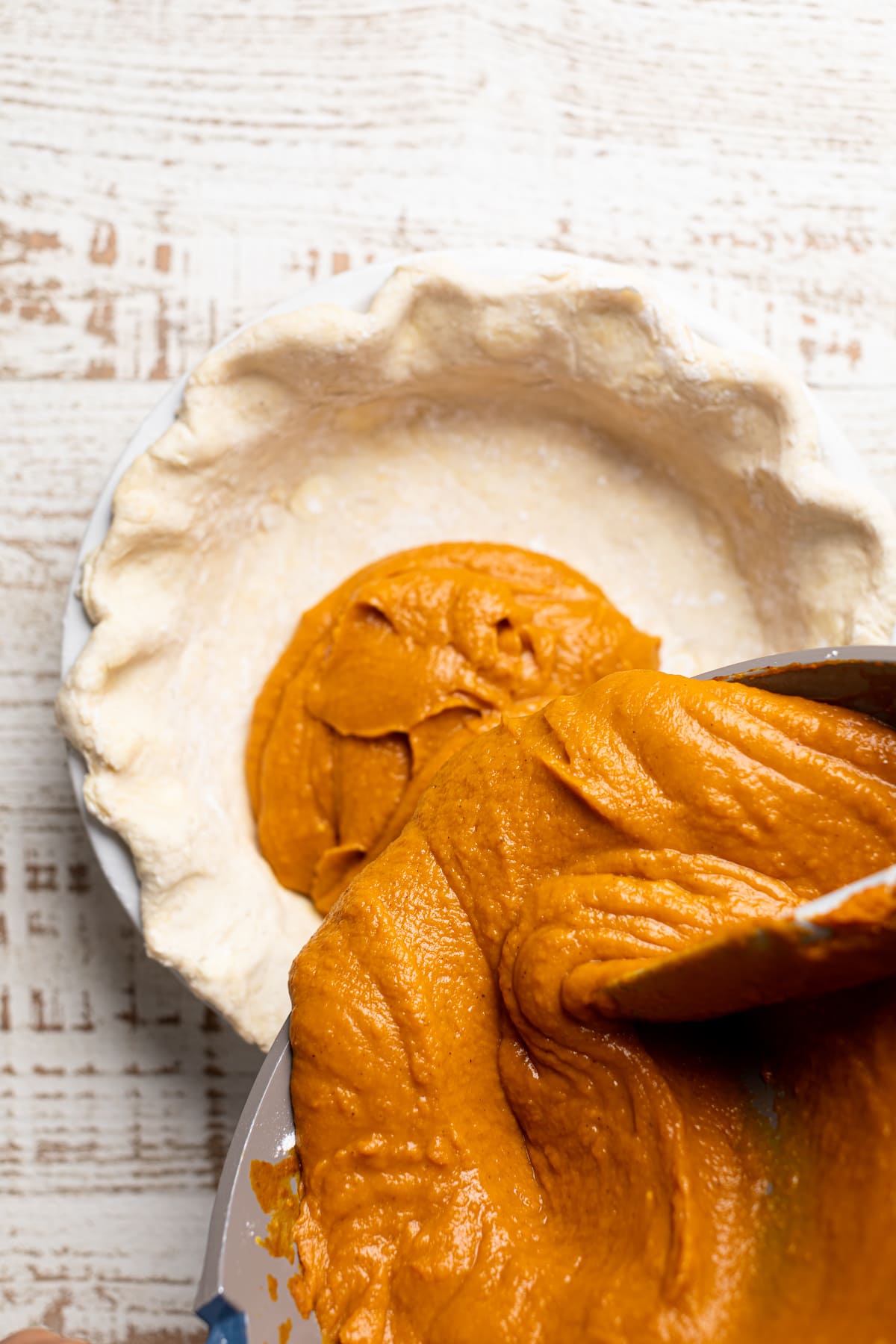 Vegan Pumpkin Pie filling pouring into a pie crust.