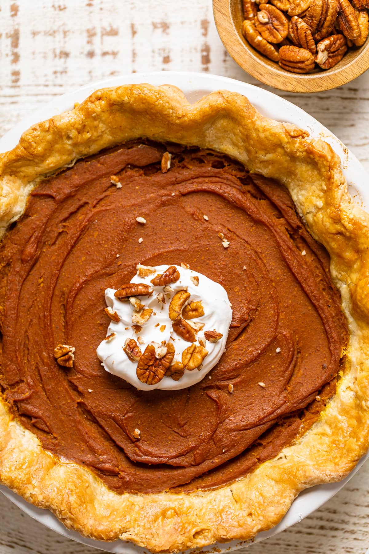 Vegan Pumpkin Pie topped with nuts and whipped cream.