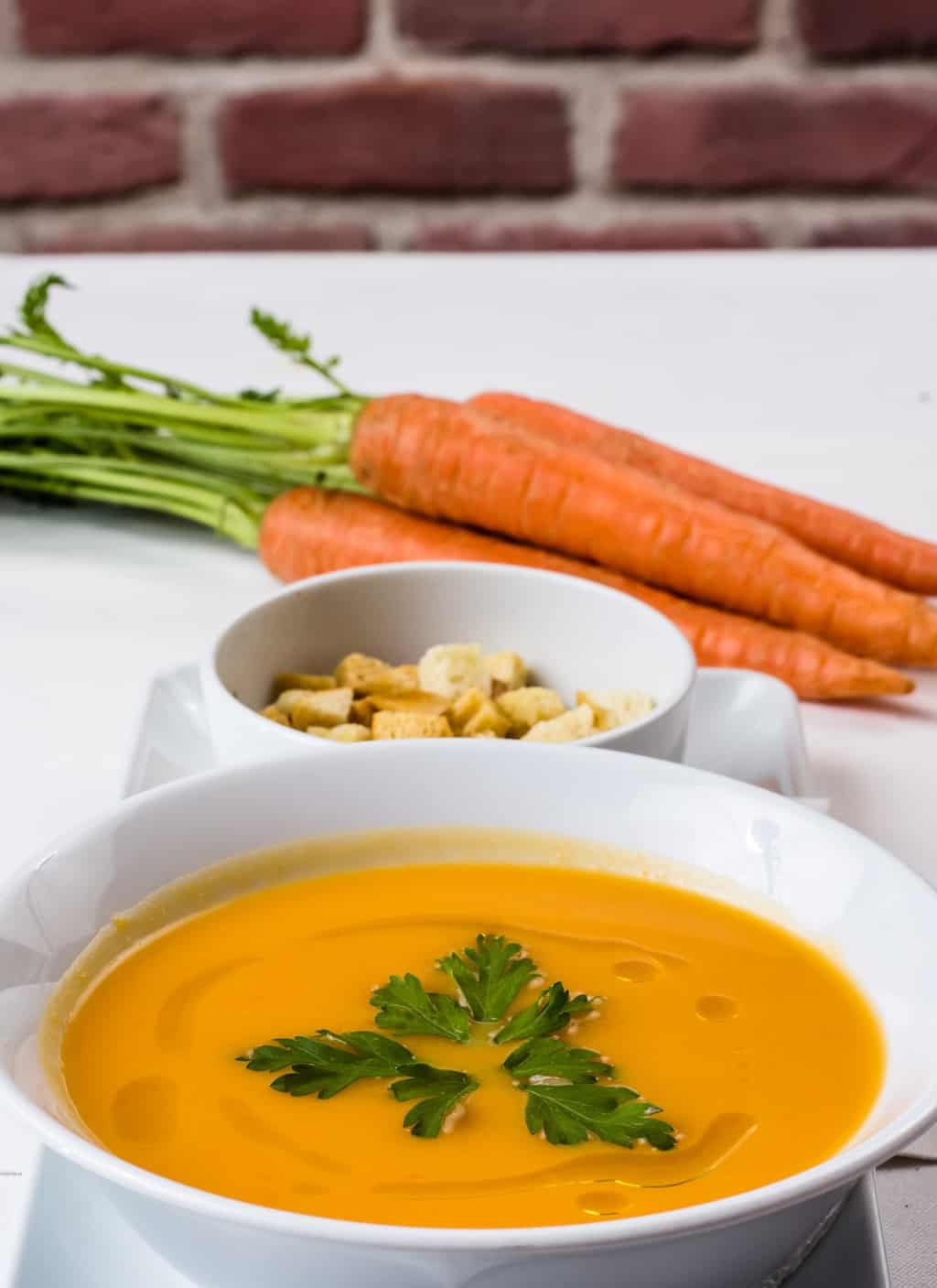 Bowl of soup on a table with carrots.