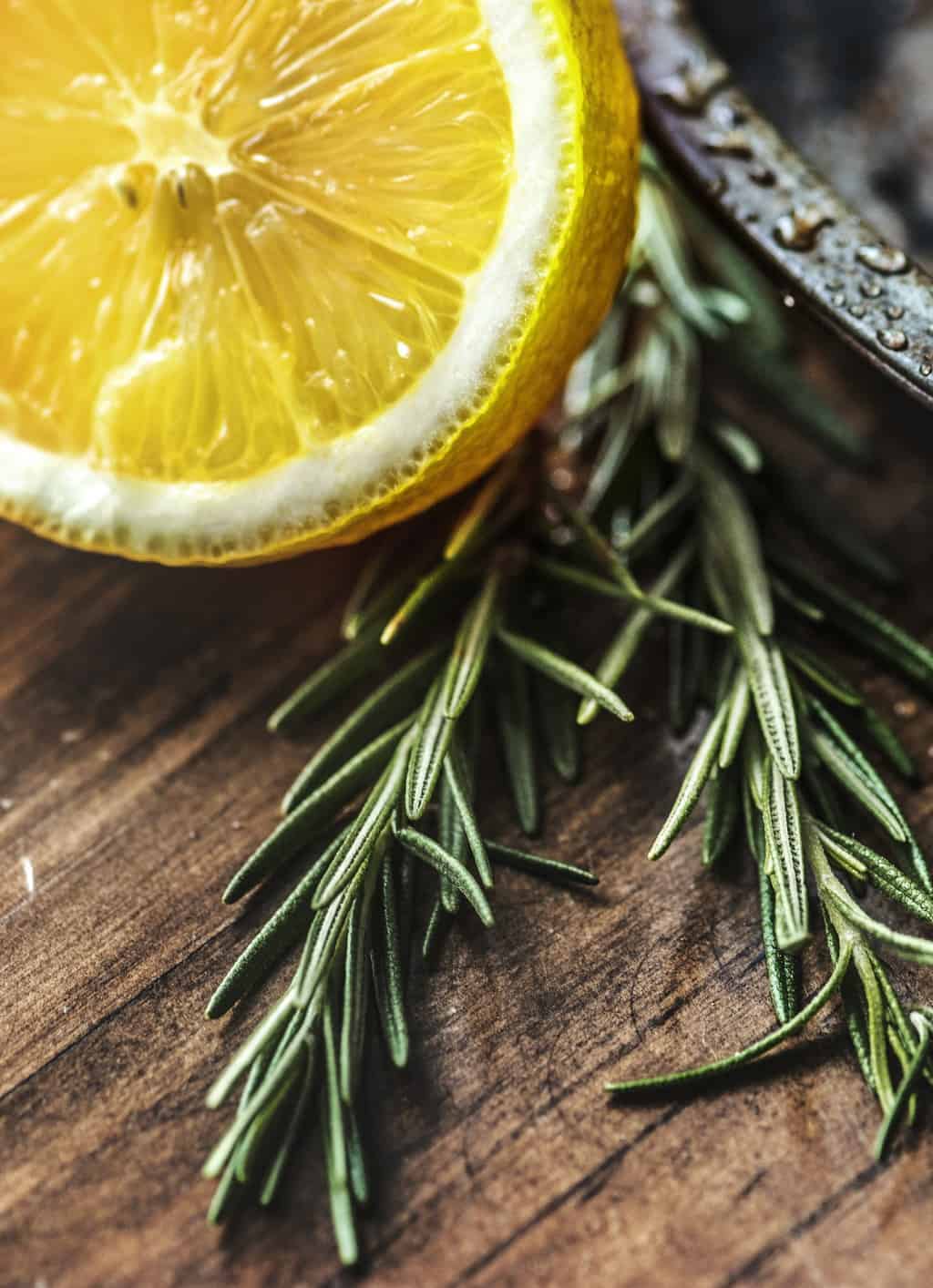 Rosemary sprigs with a sliced citrus fruit.
