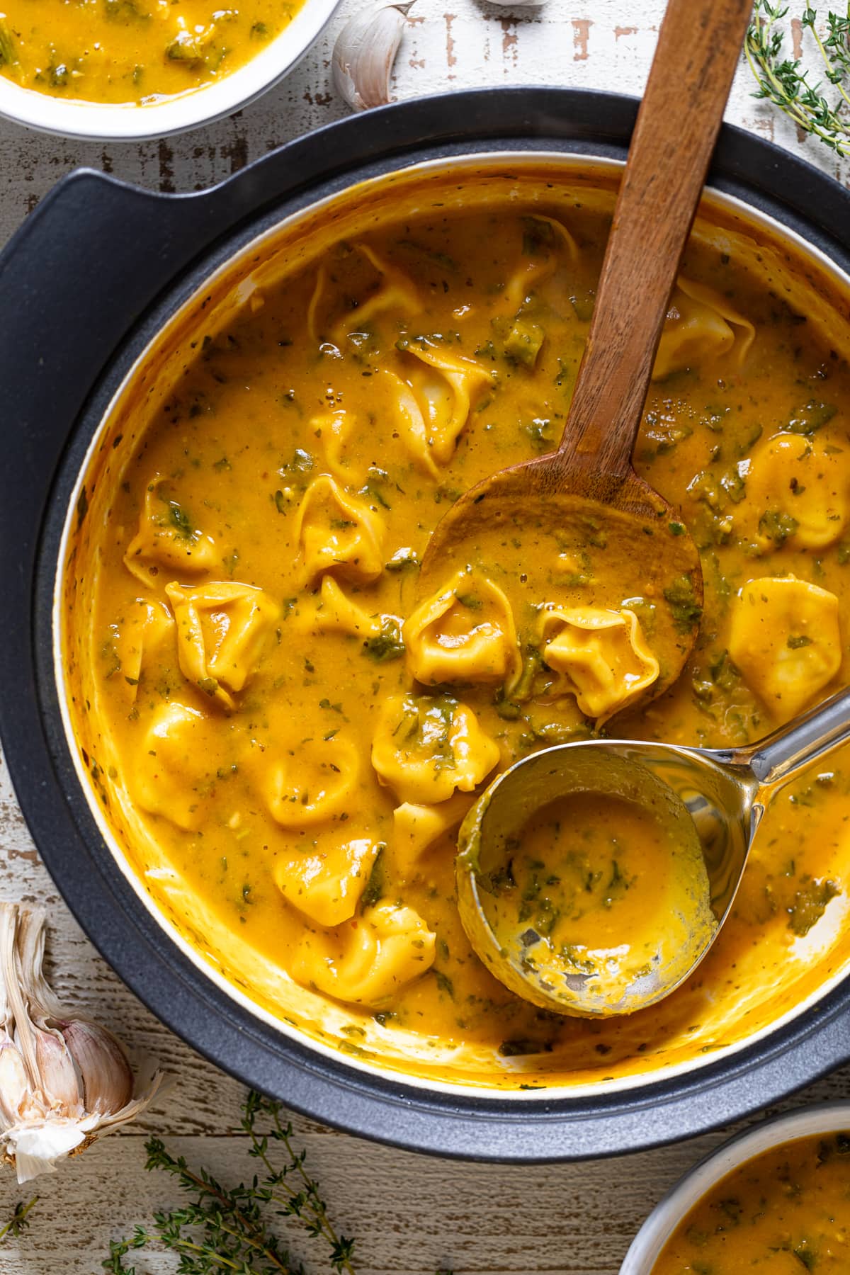 Wooden spoon and ladle in a pot of Creamy Cajun Pumpkin Tortellini Soup