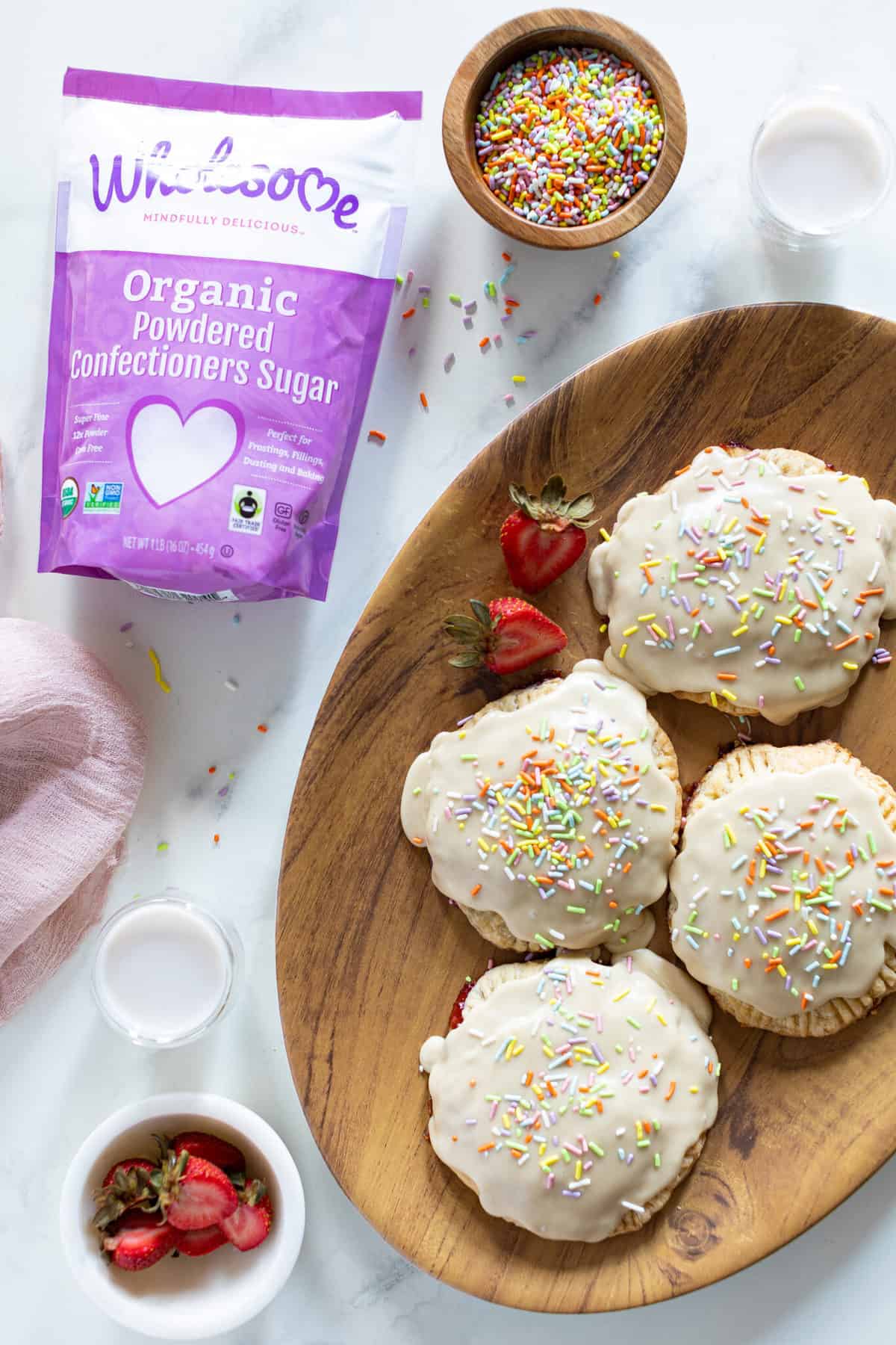 Homemade Vegan Strawberry Pop Tarts on a plate next to a bag of Wholesome organic powdered sugar.